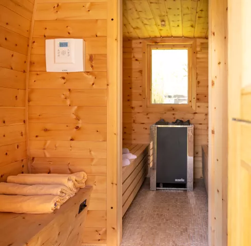 Vorraum der Sauna mit Blick in die Sauna ausgestattet mit Handtüchern und Saunagasofen